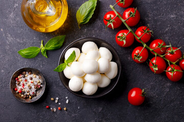 Mozzarella cheese balls with fresh tomatoes and basil. Dark background. Top view.