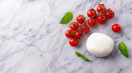 Mozzarella cheese ball with cherry tomatoes and basil leaves. Marble background. Copy space. Top view.