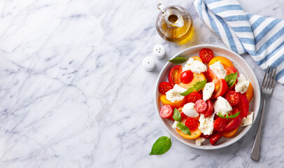 Tomato salad with mozzarella cheese and fresh basil. Marble background. Copy space. Top view.