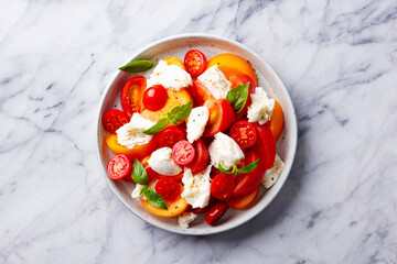 Tomato salad with mozzarella cheese and fresh basil. White marble background. Close up. Top view.