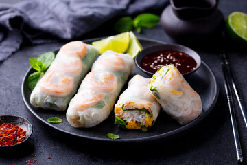 Vietnamese spring rolls with shrimps and vegetables with on a black plate. Dark background. Close up.
