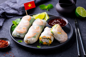 Vietnamese spring rolls with shrimps and vegetables with on a black plate. Dark background. Close up.