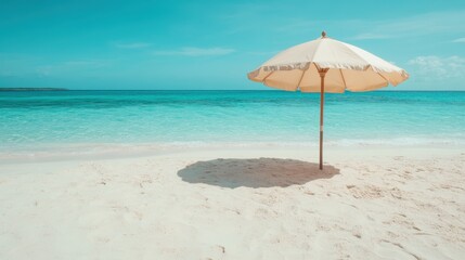 A solitary white beach umbrella gracefully stands on a pristine sandy beach, under a clear blue sky, overlooking the tranquil, turquoise waves of the vast ocean.