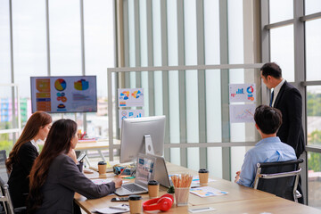 Asian businessman presenting business plans and strategies to team members in an office setting, emphasizing collaboration and corporate growth during a formal meeting aimed at teamwork success.