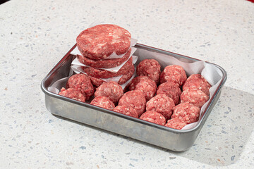 Semi finished patties and meatballs in a metal tray