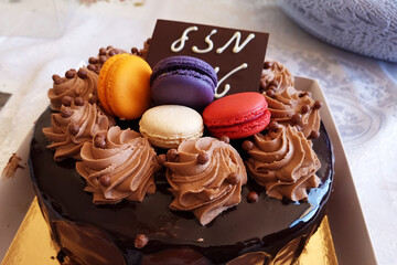 Chocolate birthday cake with chocolate decoration and Mozal Tov lettering on the table background. Dessert concept background.