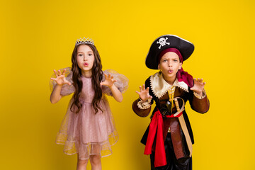 Portrait of two small kids scare boo halloween pirate princess costume isolated on yellow color background