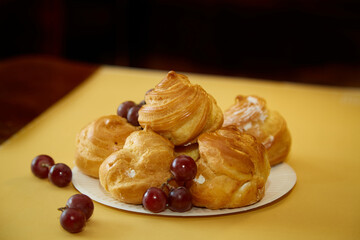 Exquisite dessert: profiteroles with grapes on a white plate, high-resolution image.