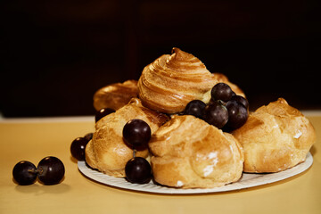 A combination of profiteroles and grapes on a white plate, close-up for restaurant or culinary projects