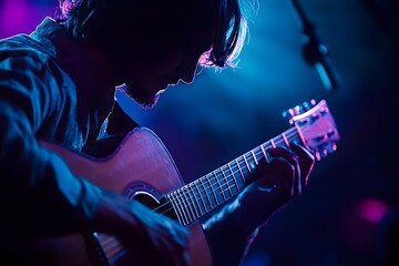 Obraz premium A man plays a guitar on stage in a dimly lit room.