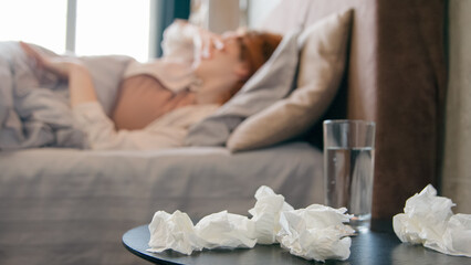 Unhealthy sick ill Caucasian woman sneeze in bed at home bad feeling coronavirus cold flu disease girl suffer headache fever seasonal virus allergy blowing runny nose in tissue napkin health problem