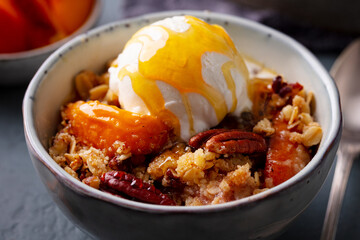Crumble cake with peach fruit and ice cream in bowl. Close up.