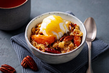 Peach crumble cake with ice cream in bowl. Grey background. Close up.