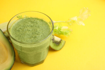 Delicious green smoothie and ingredients on yellow table, closeup. Space for text
