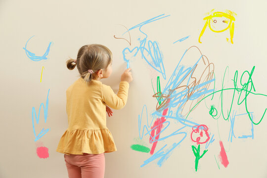 Naklejki Little child drawing on white wall, back view