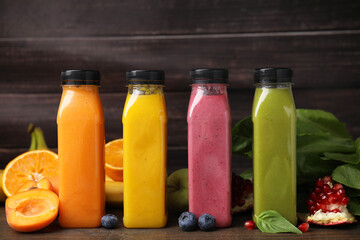 Glass bottles of tasty smoothies and different products on wooden table