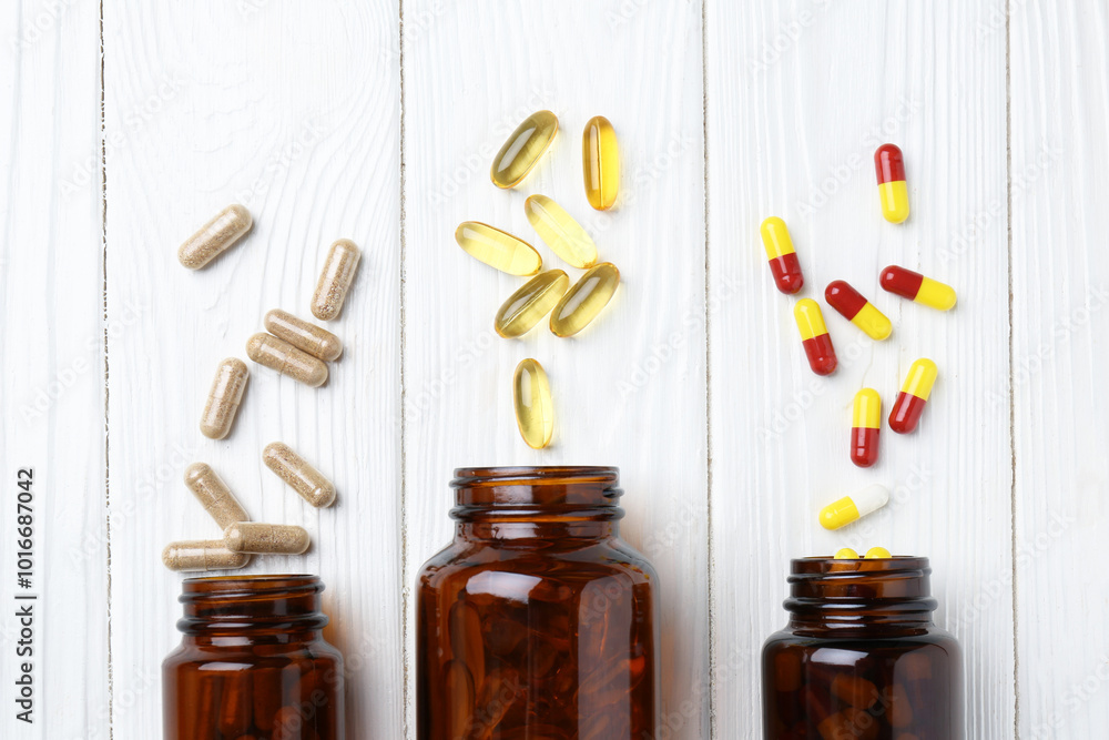 Wall mural Pharmacist. Many different pills and overturned bottles on white wooden table, flat lay