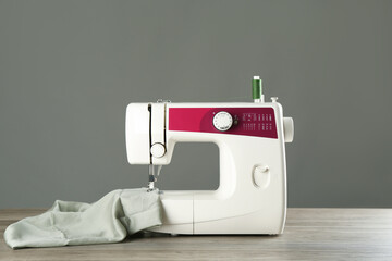 One sewing machine with fabric on wooden table against grey background