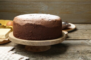 Tasty chocolate sponge cake with powdered sugar on wooden table