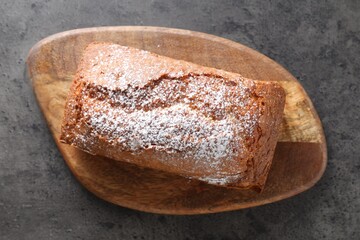 Tasty sponge cake with powdered sugar on grey table, top view
