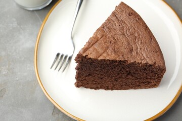 Piece of tasty chocolate sponge cake served on grey table, closeup