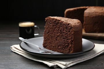 Piece of tasty chocolate sponge cake served on wooden table, closeup