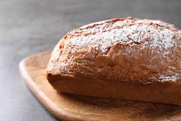 Tasty sponge cake with powdered sugar on grey table, closeup