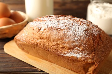 Tasty sponge cake with powdered sugar on wooden table, closeup