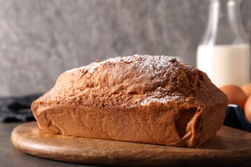 Tasty sponge cake with powdered sugar on grey table, closeup