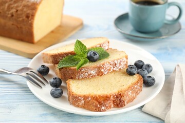 Freshly baked sponge cake, blueberries and mint on light blue wooden table, closeup