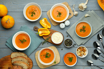 Flat lay composition with delicious pumpkin soup on gray wooden table