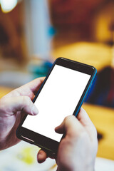 Cropped view of man's hands typing text information on modern smartphone device with blank mock up screen area for website.Selective focus on digital mobile phone with copy space for internet content