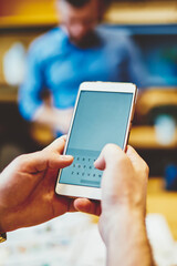 Cropped view of male hands with luxury watches holding modern smartphone device with business people on background. Selective focus on mock up screen of mobile phone,  online banking application
