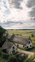Fototapeta premium Serene landscape featuring rustic farmhouses surrounded by lush fields and a cloudy sky, capturing rural tranquility.