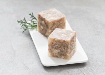 Jellied Meat in the shape of a cube. On a plate. 