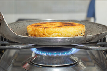 A cheese arepa on a frying pan on the stove. Breakfast in Colombia. Colombian food concept.