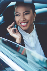 Cheerful female commuter talking on backseat in car using 4g wireless internet connection for online phoning to friend, positive woman making international conversation during car trip to office