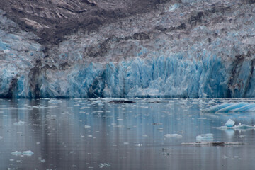 Close range Glacier with floating ice drifting into the foreground, streaked reflections cascading vertically into the chilled waters.