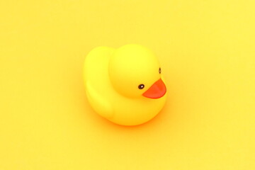 A yellow rubber duck stands on a yellow background.