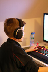Close up of a teenage boy playing a game on the computer with headphones on
