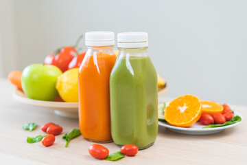 Orange, green detox juice in glass jars, bottle of vegetable fresh ingredients on table, carrot smoothie for diet, drinking healthy meal food for weight loss. Detox breakfast, isolated on background.
