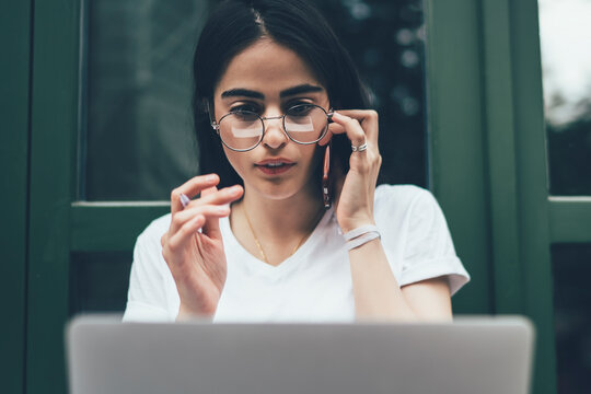 Amazed female software developer in optical spectacles wonder with mistake in program code calling to colleague for online consultancy while working remotely, skilled woman reading shocked news