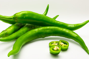 A green and white with greens and peppers. Food fresh healthy concept. Close up of hot chilies and greens on white. Close up of red peppers, greens, and red chili peppers on white lifestyle.