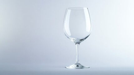 Obraz premium Elegant empty wine glass against a soft light background, symbolizing sophistication and simplicity in modern dining.