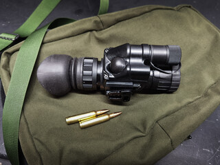 Night vision monocular and 5.56x45mm cartridges, close-up photo.