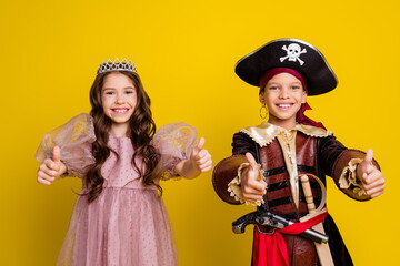 Portrait of two small kids halloween pirate princess costume show thumb up isolated on yellow color background