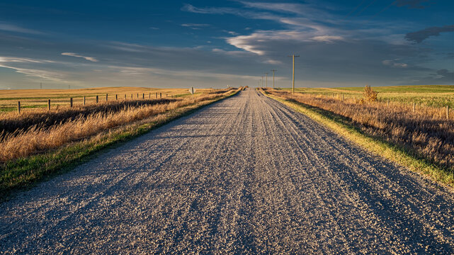 A northward view along Range Road 270's gravel vanishing point near the junction with Township Road 222 and Canadian Pacific's controlled level railway crossing, Rocky View County, Alberta, Canada.