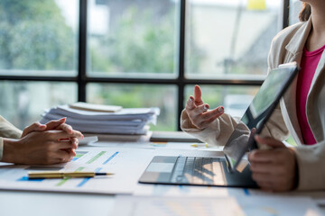 Businesswomen using laptop and digital tablet discussing over financial chart at office desk