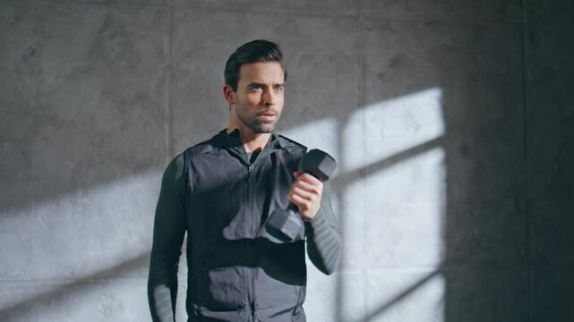 Strong athlete lifting dumbbells in loft studio closeup. Man exercising sport