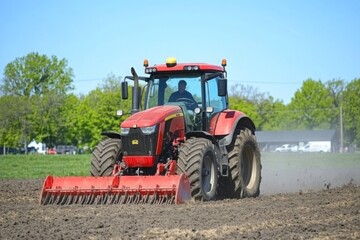 Fototapeta premium A tractor diligently plowing a field under a clear blue sky, showcasing the beauty of agricultural life. The bright daylight highlights the rich soil being turned